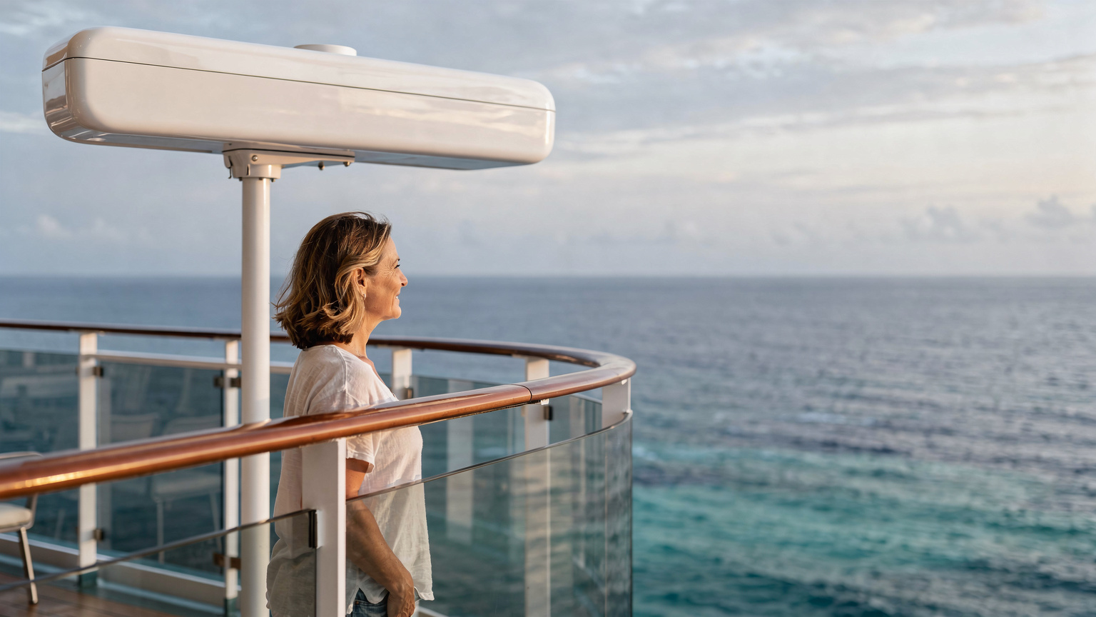 Ein Passagier schaut von einem Balkon eines Kreuzfahrtschiffes aufs offene Meer, während ein Starlink-Terminal auf dem Deck des Schiffes im Vordergrund leicht erkennbar ist.